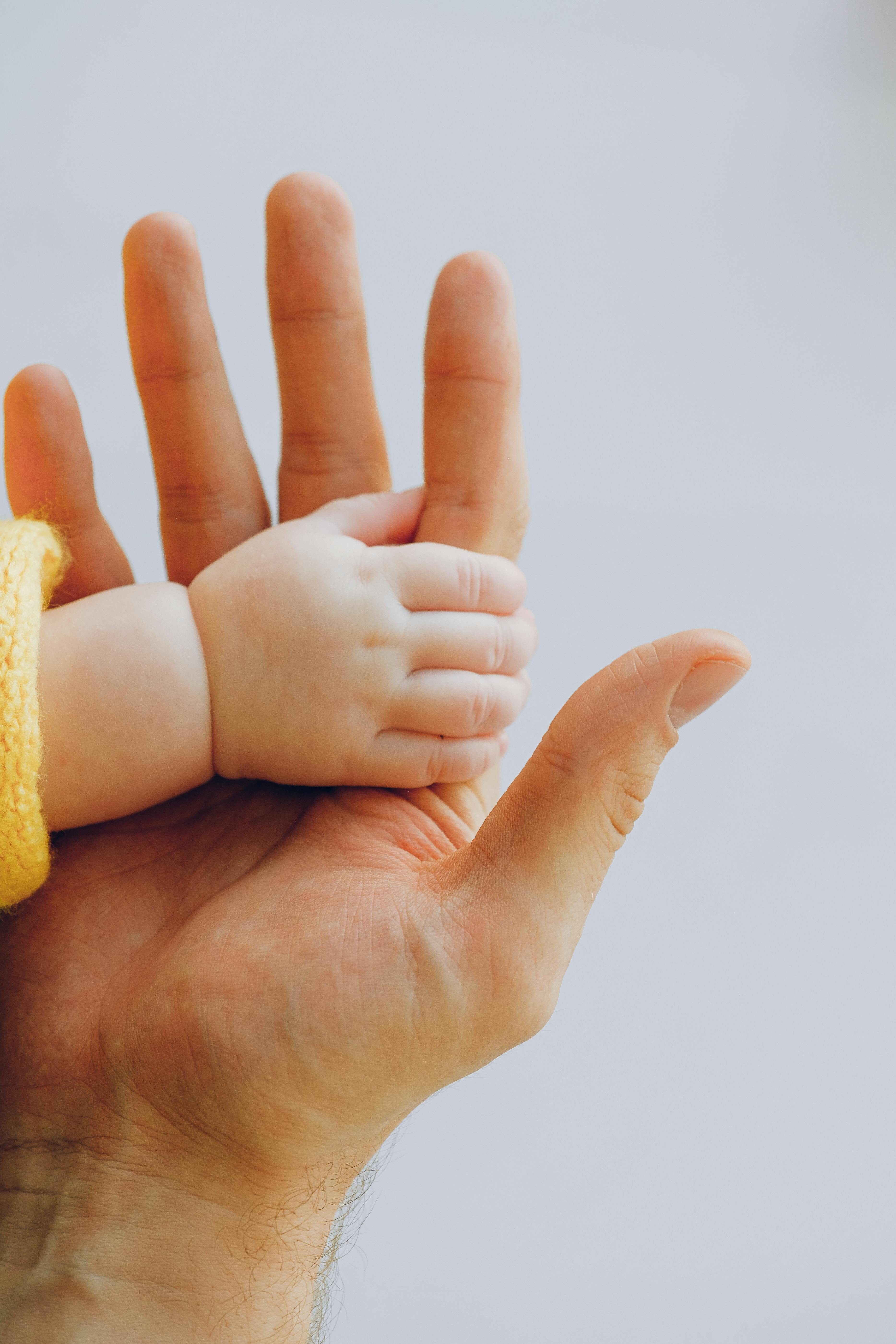 un bébé qui serre la main de son papa